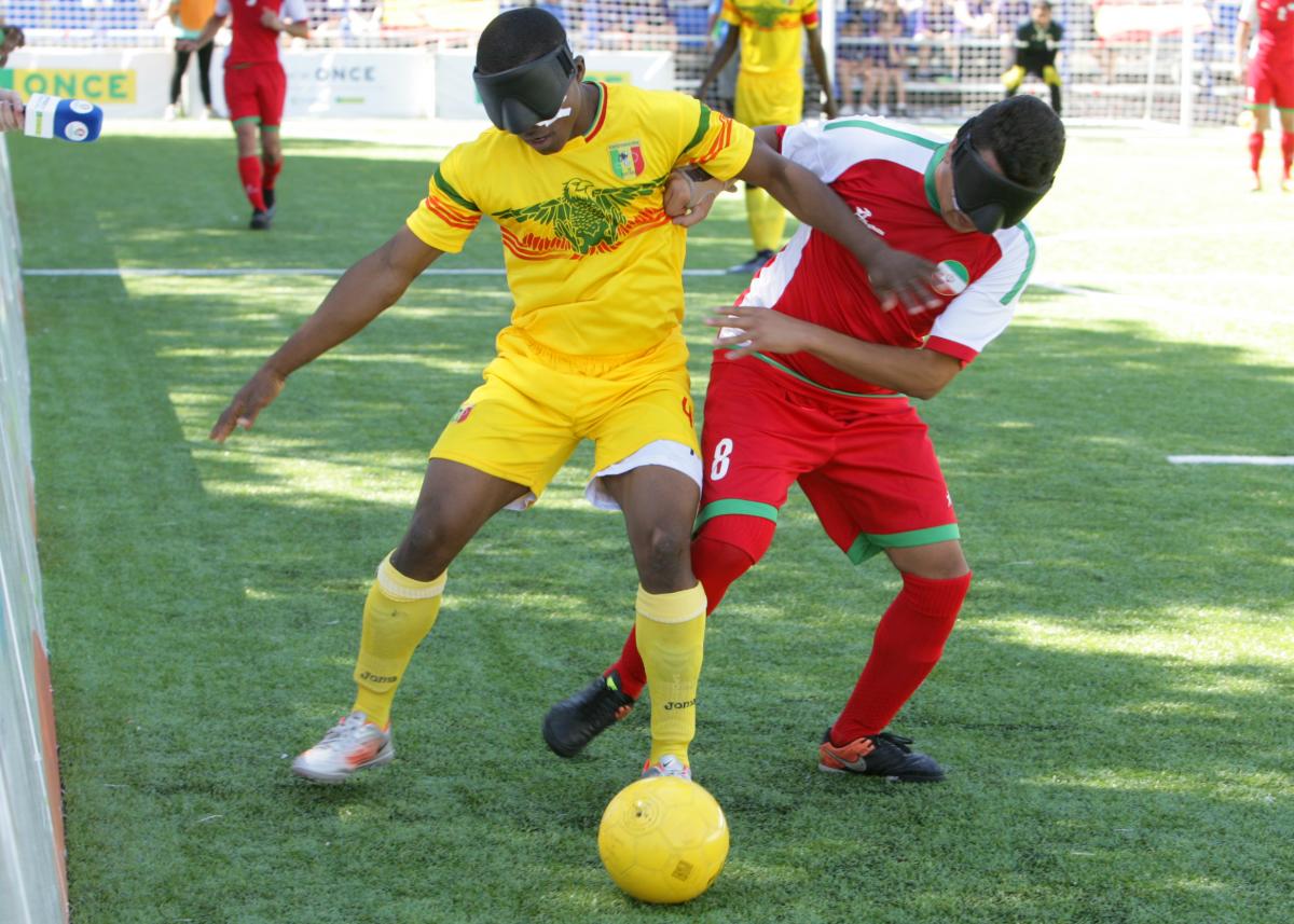 Two blind football players battle for the ball