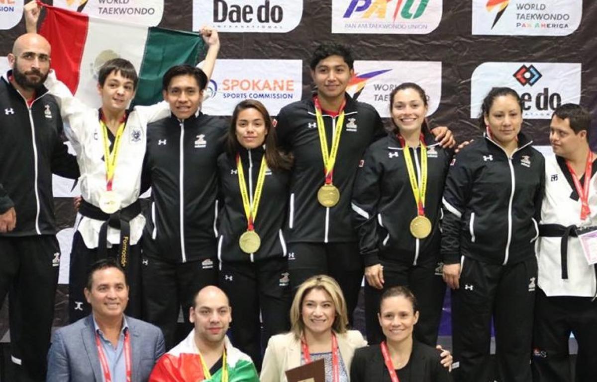 a group of male and female Para taekwondo fighters standing together with gold medals round their necks