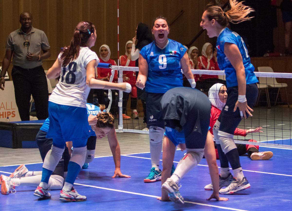 three female Italian sitting volleyball players celebrate on the court