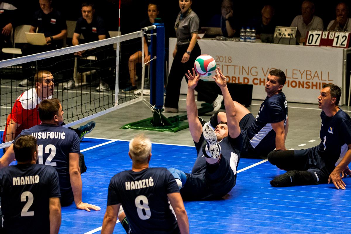 a group of Bosnian male sitting volleyball players working to get the ball back over the net