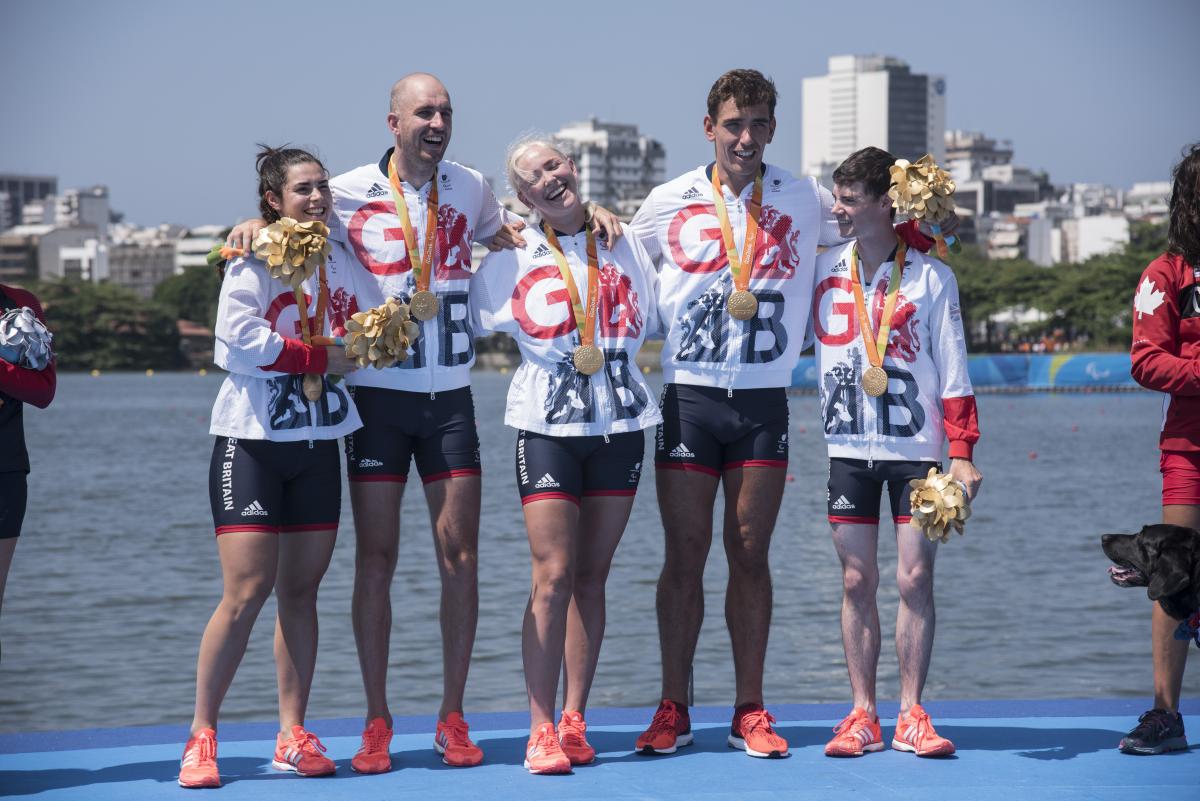 Great Britain Rio 2016 rowing team a group of five British Para rowers standing on the podium with their gold medals