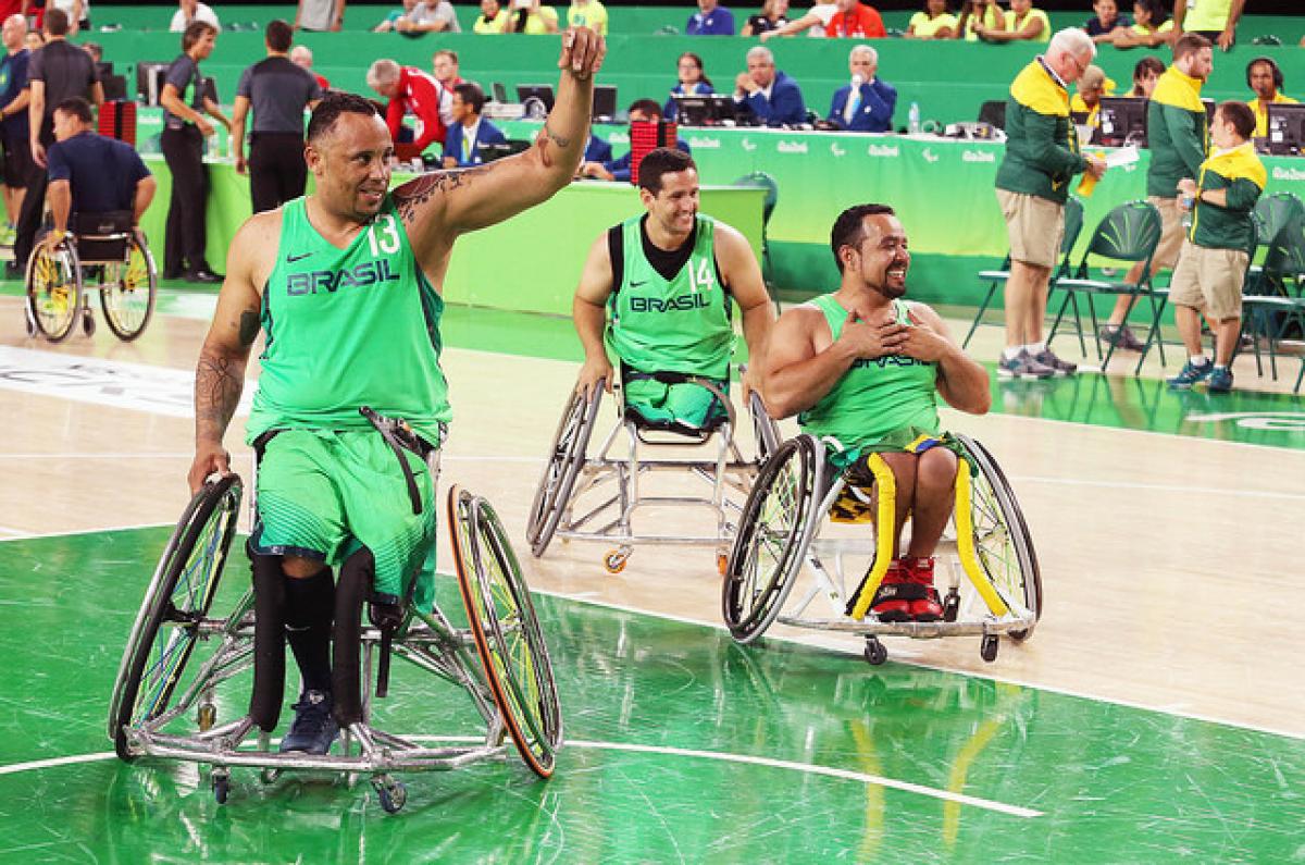 Three Brazilian men wheelchair basketball players wave at home crowd