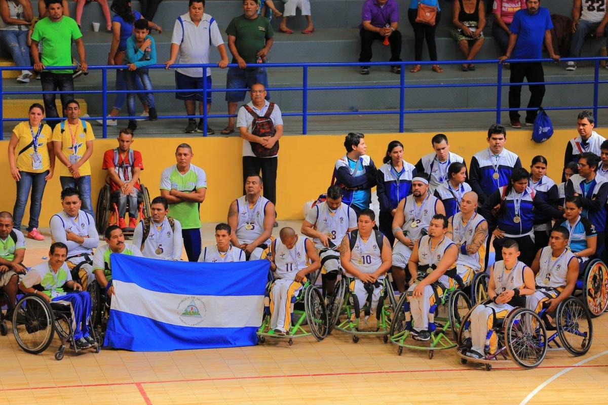 Nicaragua's wheelchair basketball players on a court holding up the Nicaragua flag