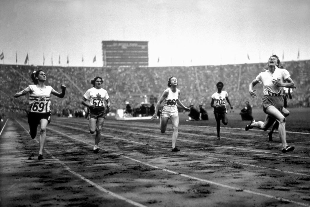 female sprinter Fanny Blankers-Koen crosses the finish line ahead of other female runners