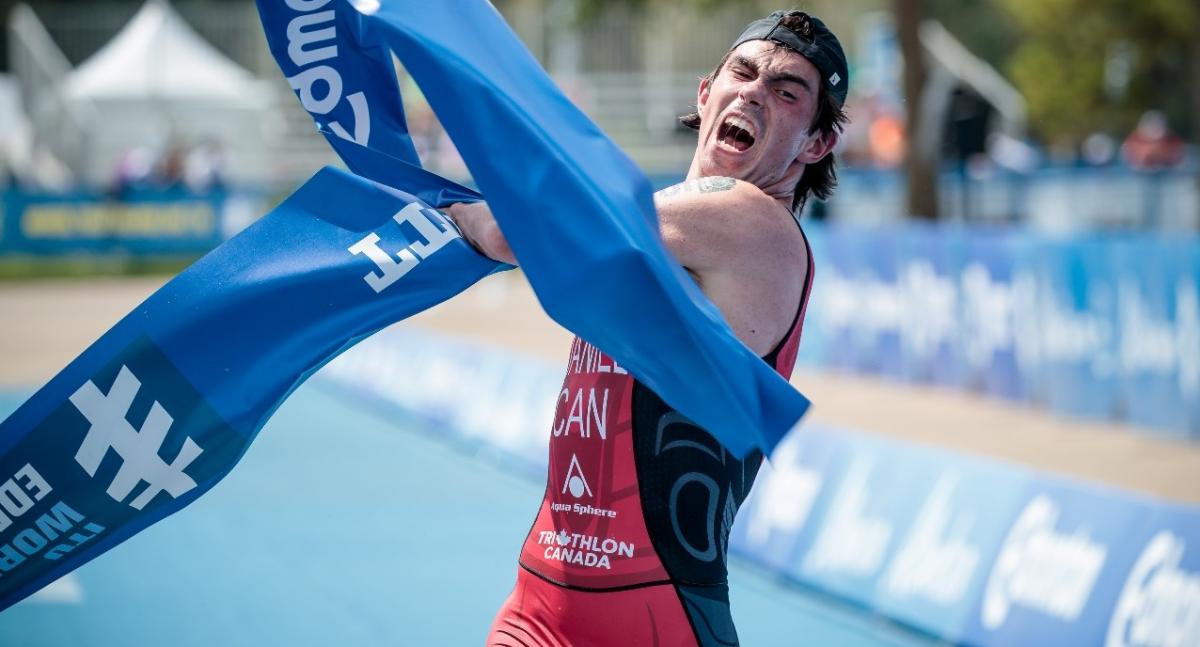 male Para triathlete Stefan Daniel rips the tape at the finishing line as he crosses to win the race