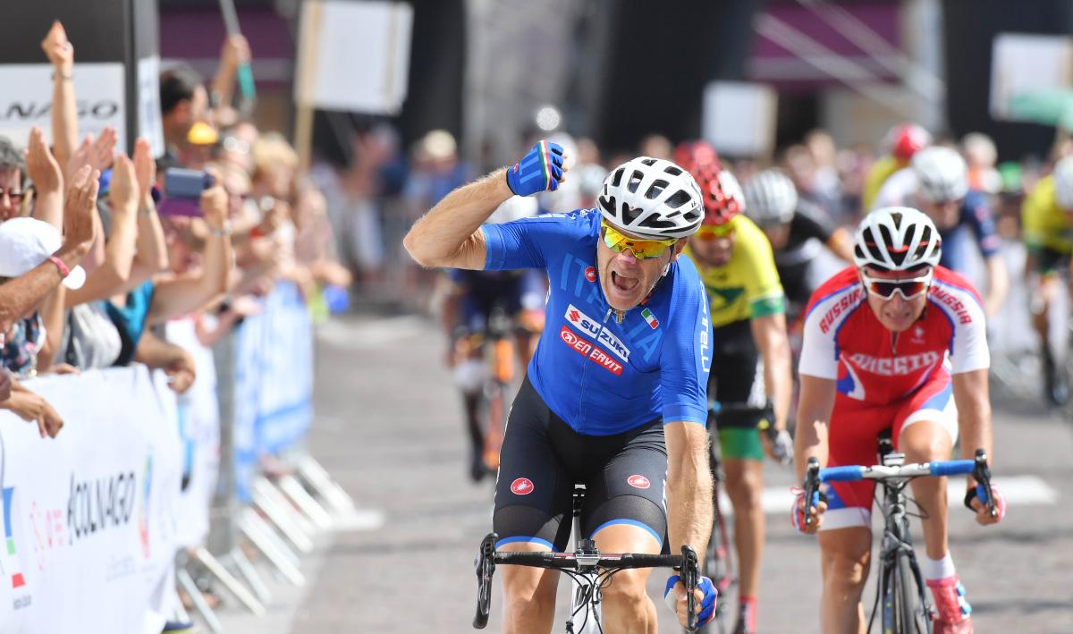 male Para cyclist Michele Pittacolo punches the air as he crosses the finish line