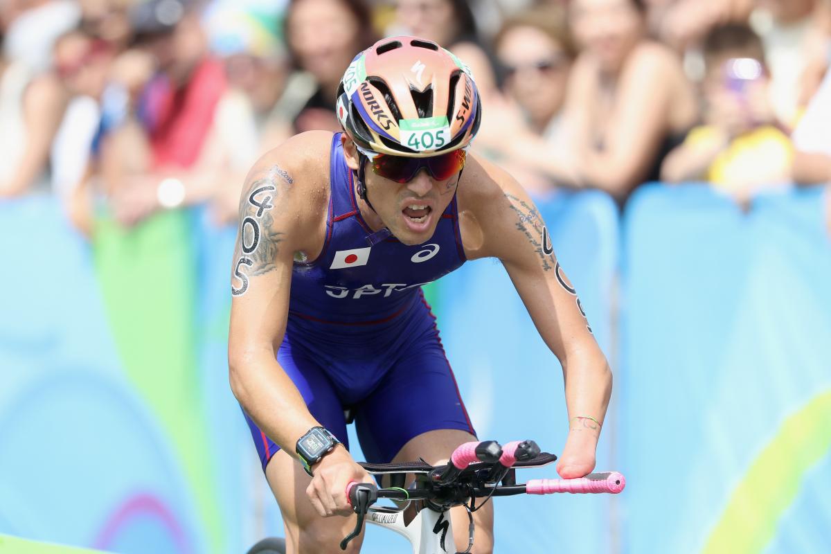 male Para triathlete Keiichi Sato racing on a bike