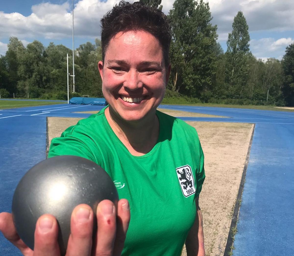 female Para athlete Birgit Kober smiling and holding a shot put