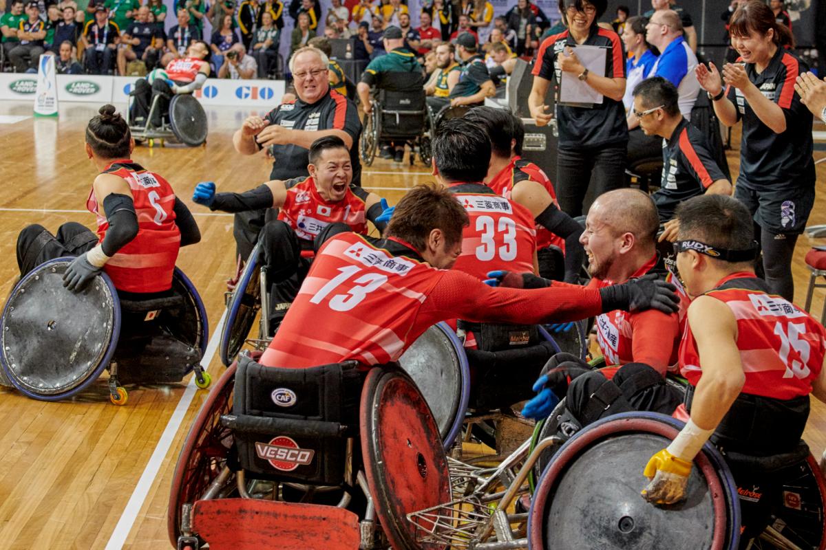 a group of Japanese wheelchair rugby players celebrate on the court