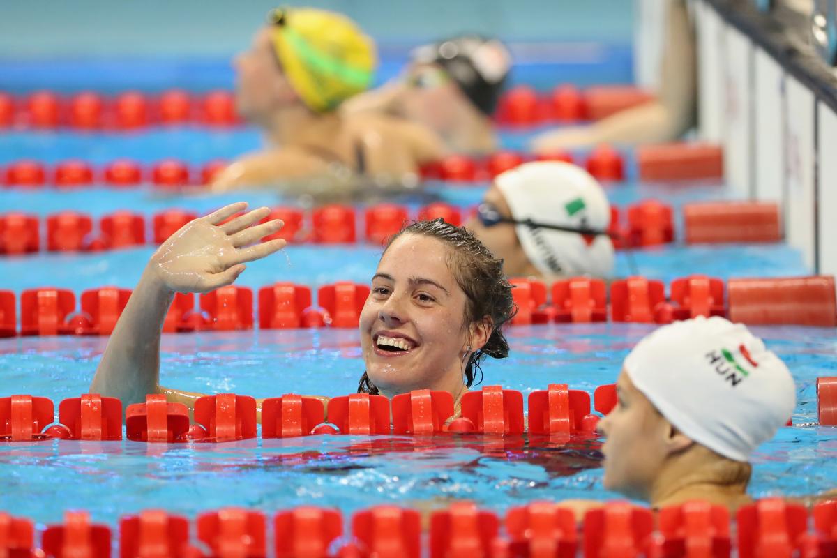 female Para swimmer Aurelie Rivard takes her swimming cap off and celebrates in the pool after winning a race