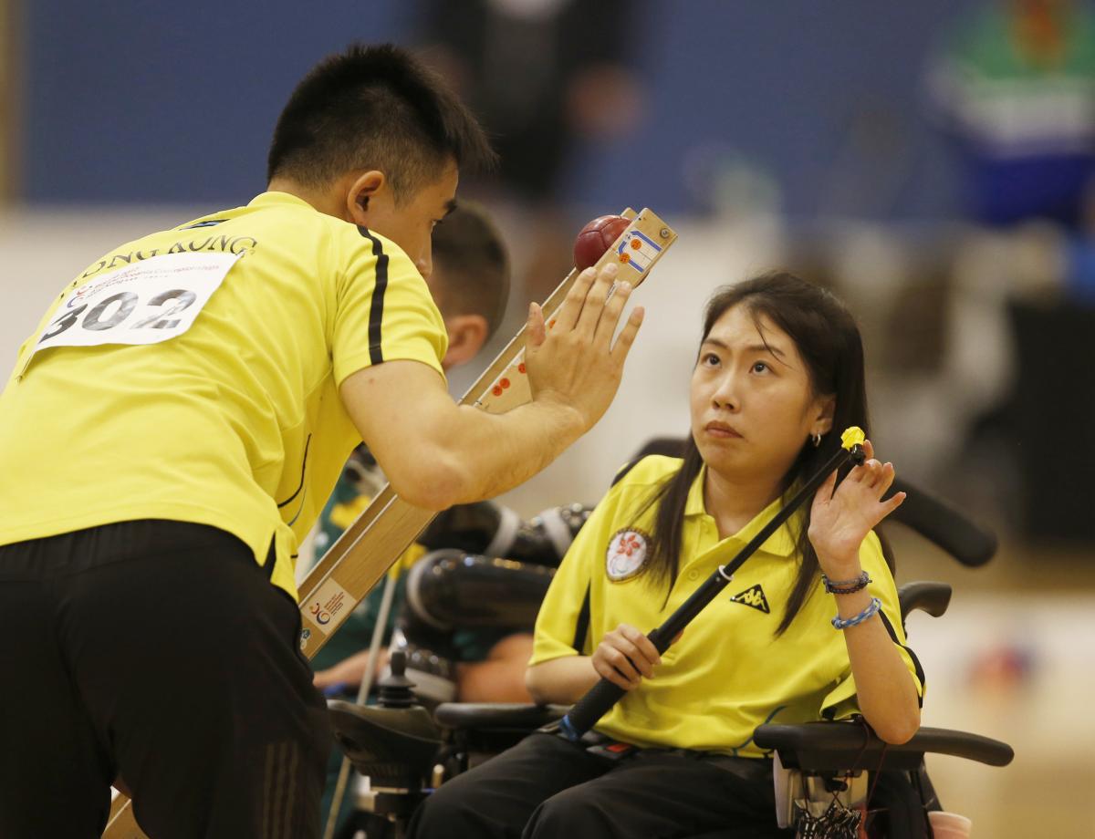 female boccia player Ho Yuen Kei listens to her coach before taking a shot