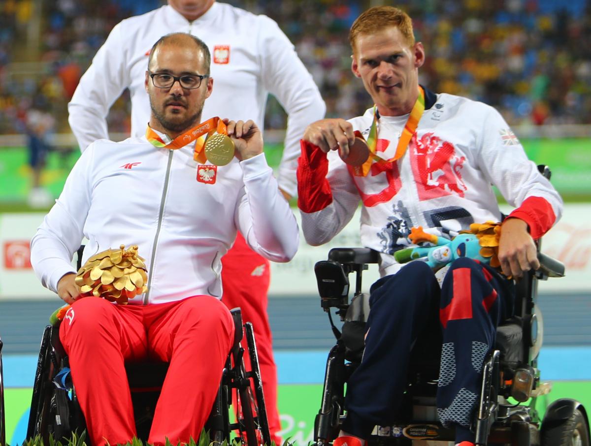male Para athletes Stephen Miller and Maciej Sochal on the podium holding up their medals