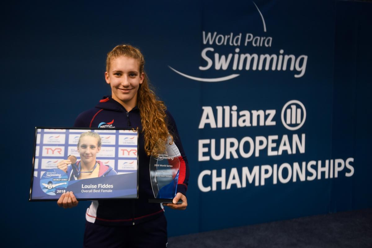 female Para swimmer Louise Fiddes smiling and holding two trophies