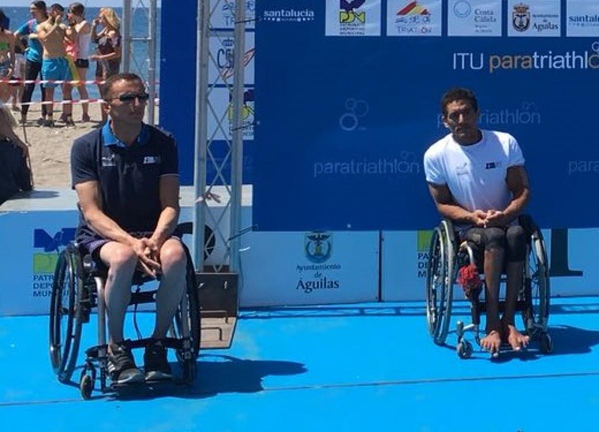 male Para triathletes Alexandre Paviza and Ahmed Andaloussi sitting on the podium