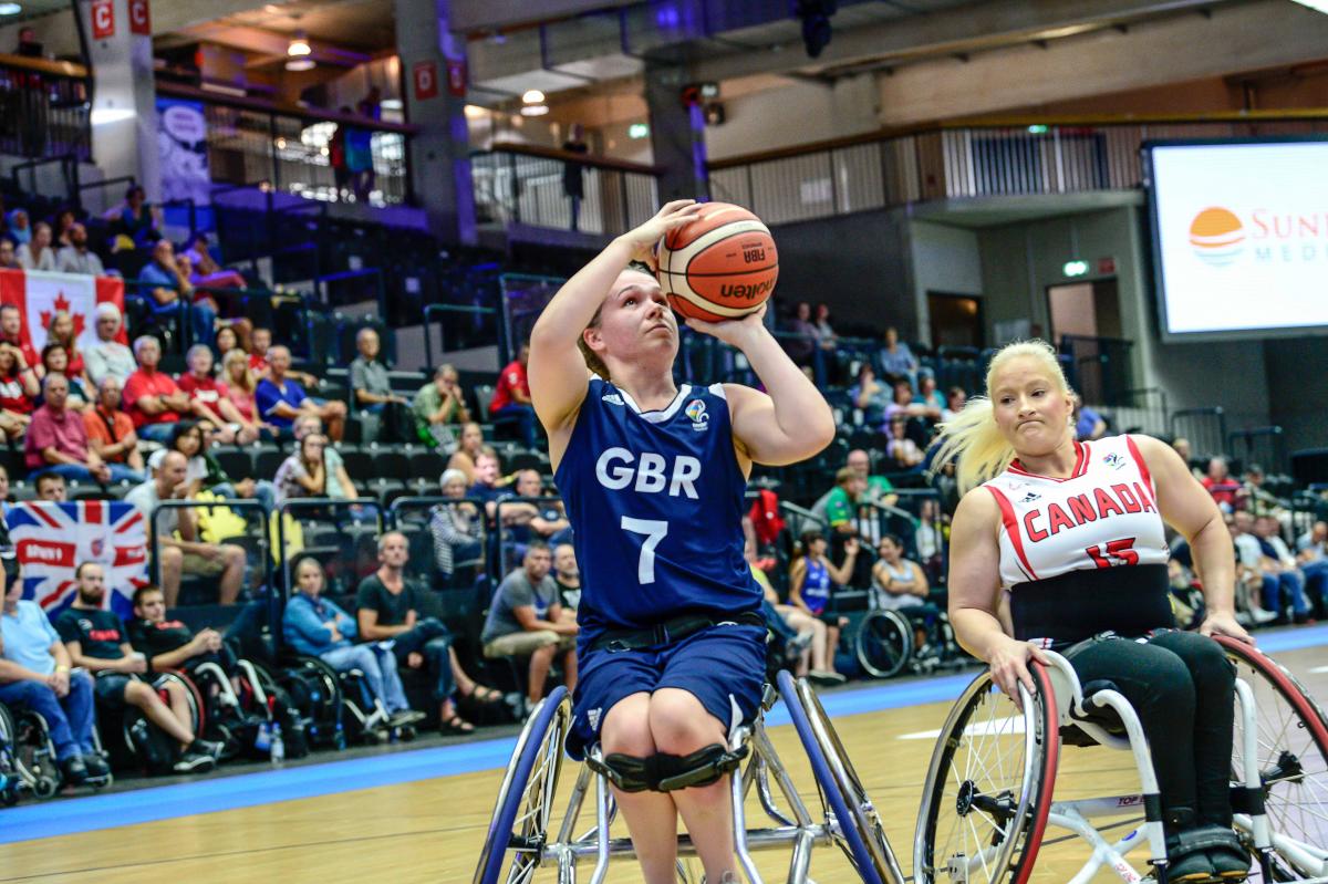 British female basketball player shoots the ball while Canadian player tries to defend