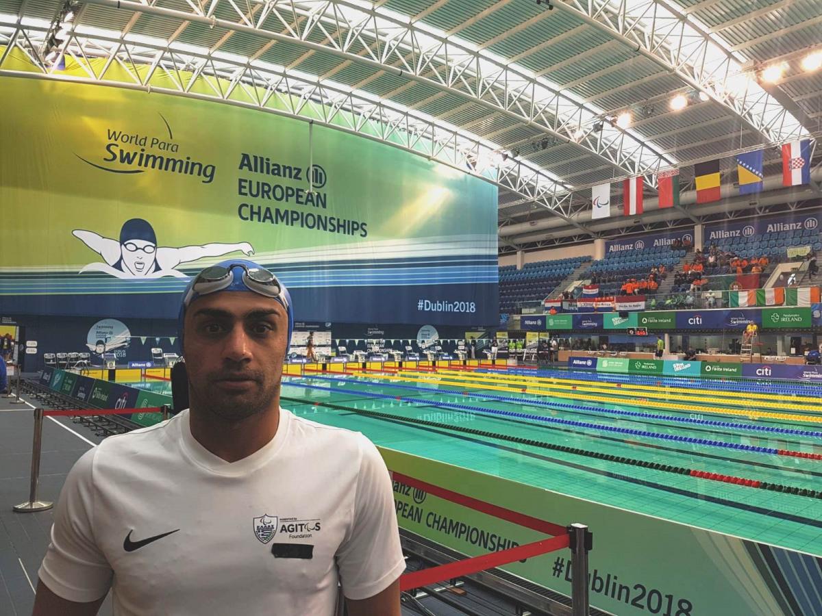 Man with swimming cap in front of a swimming pool