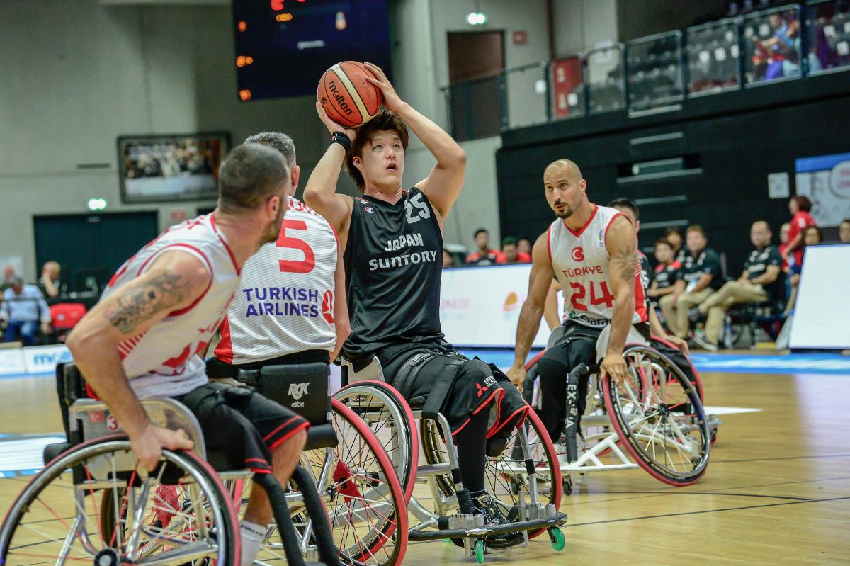 Man in wheelchair with a ball in his hands surrounded by other three men