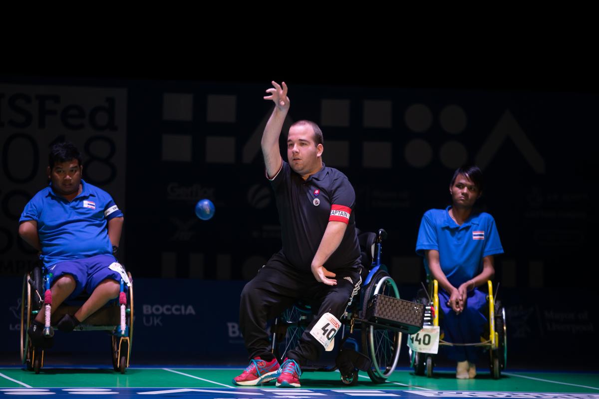 Slovakia v Thailand - BC4 Pairs final - Liverpool 2018 Boccia World Championships Men in a wheelchair throwing a blue ball observed by other two men