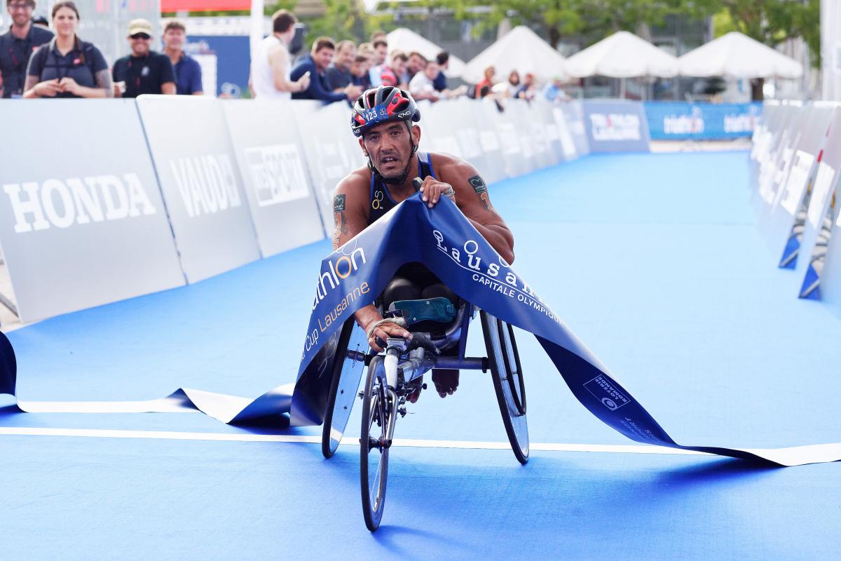 male Para triathlete Ahmed Andaloussi breaks the tape as he crosses the finish line