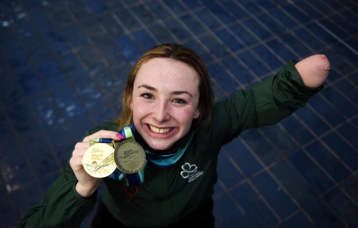 female Para swimmer Ellen Keane smiles and holds up her gold medal