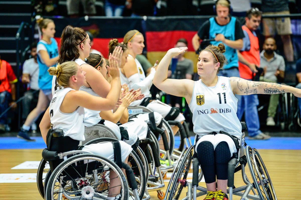 A female German wheelchair basketballer high fives her teammates