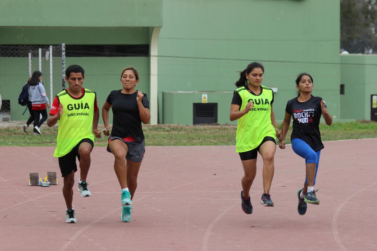 two vision impaired runners competing on the track with their guides