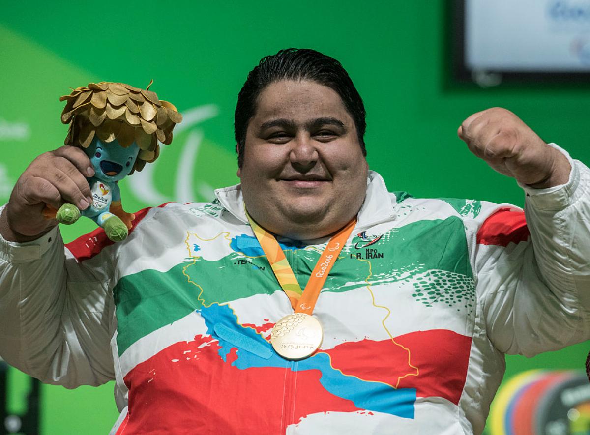 male powerlifter Siamand Rahman pumps his fist as he is wheeled onto the stage