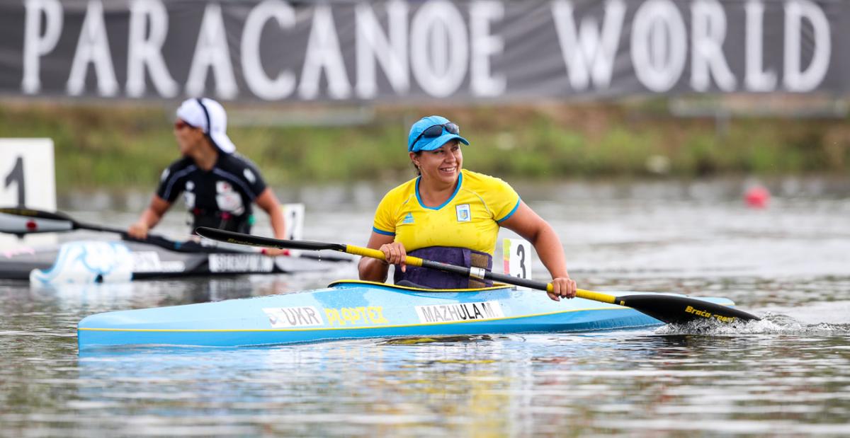 female Para canoeist Maryna Mazhula smiles in her boat after winning the race