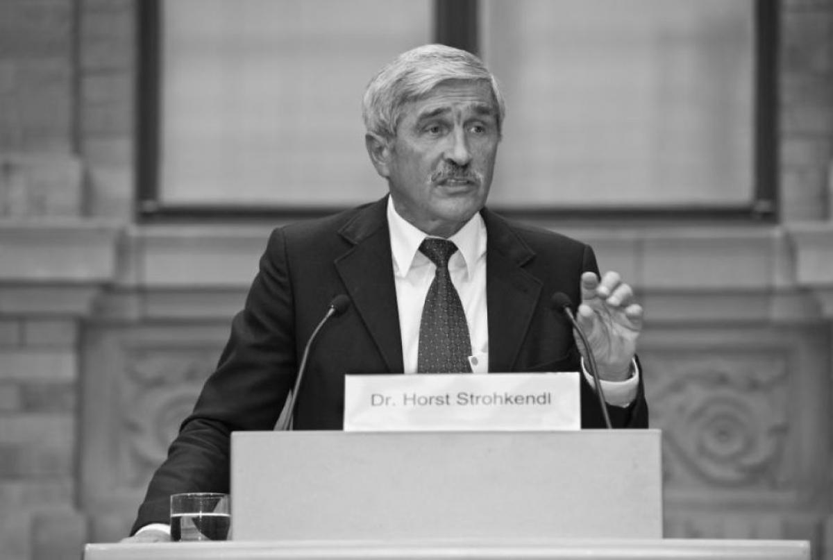 Black and white photo of a man in suit speaking at a podium 