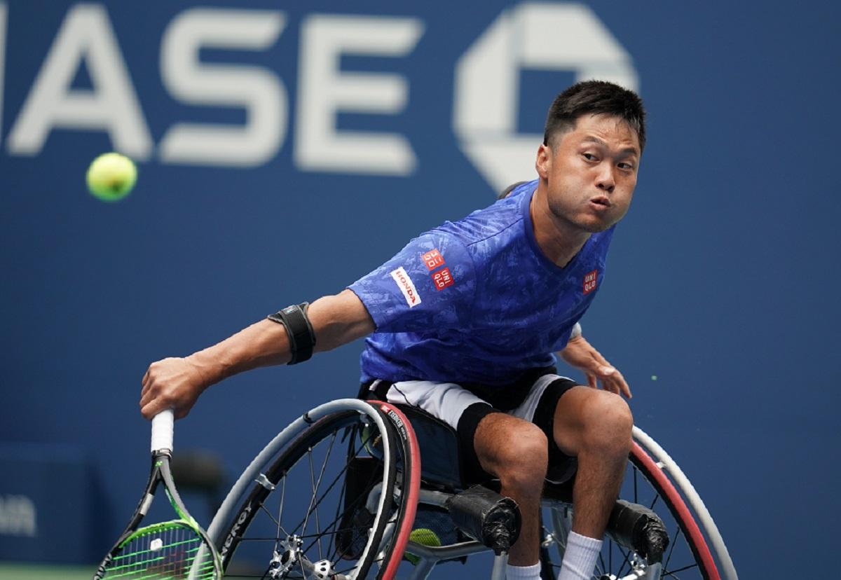 Japanese man in wheelchair reaches to his tennis ball