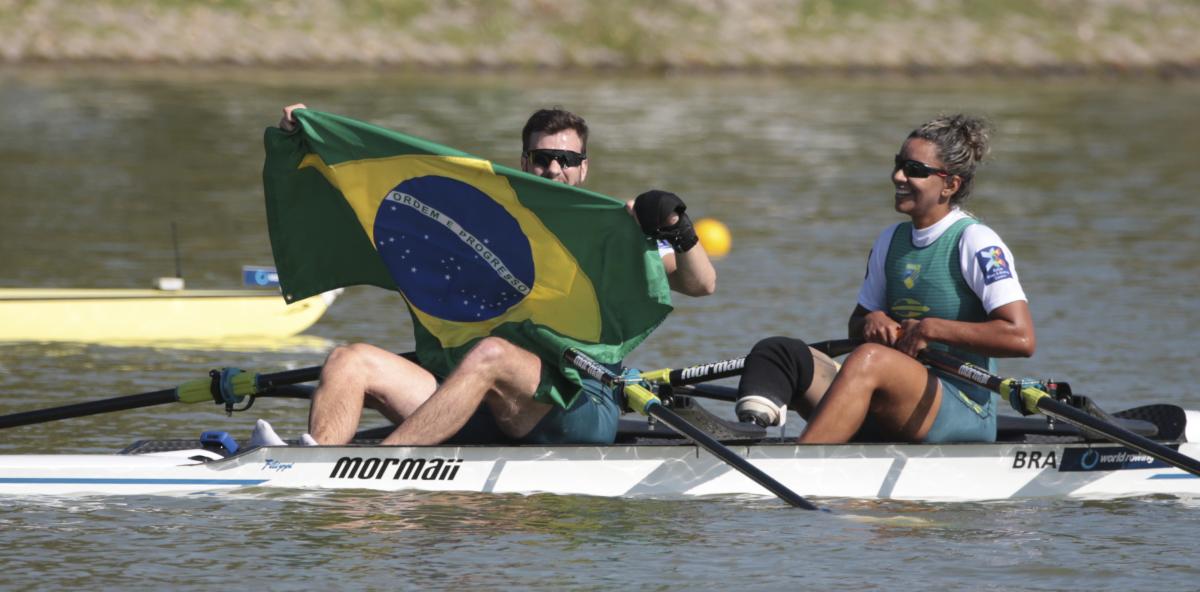 Diana Barcelos de Olivera and Jairo Klug - Brazil - rowing A man and woman in rowing boat celebrate, while man holds up Brazilian flag