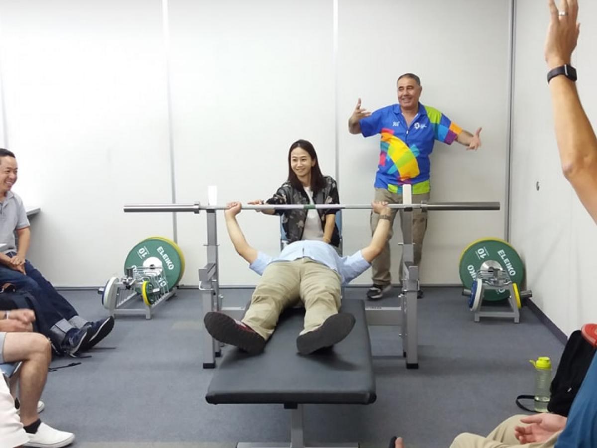an official tries out the weight of a powerlifting bar while lying on the bench