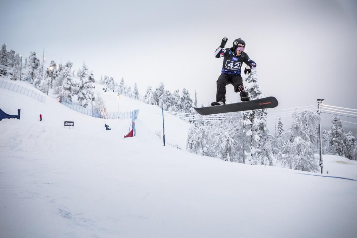 a male Para snowboarder jumps on the slope