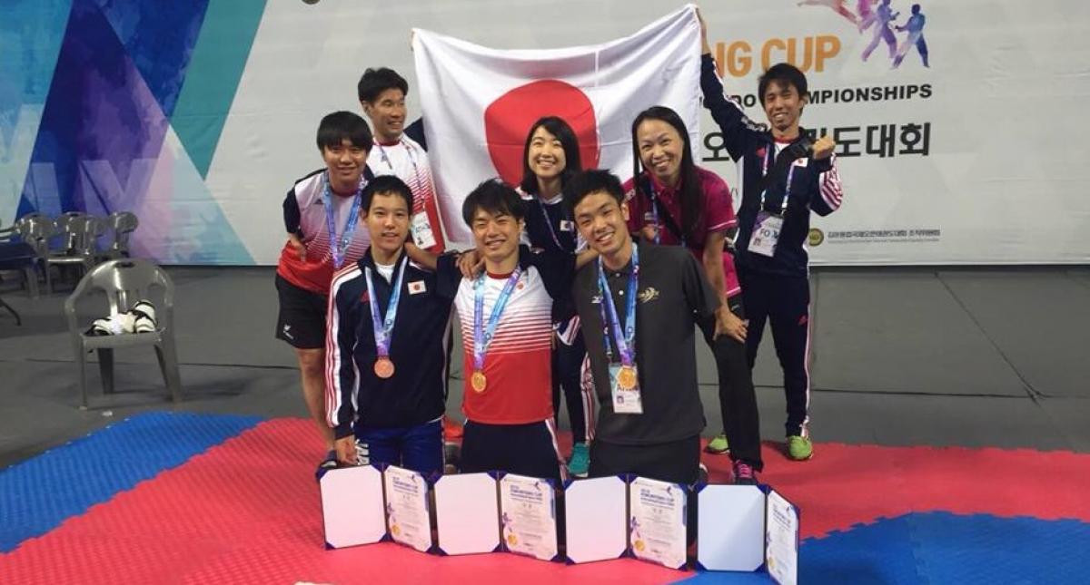 a group of Japanese Para taekwondo fighters with their medals and a Japan flag