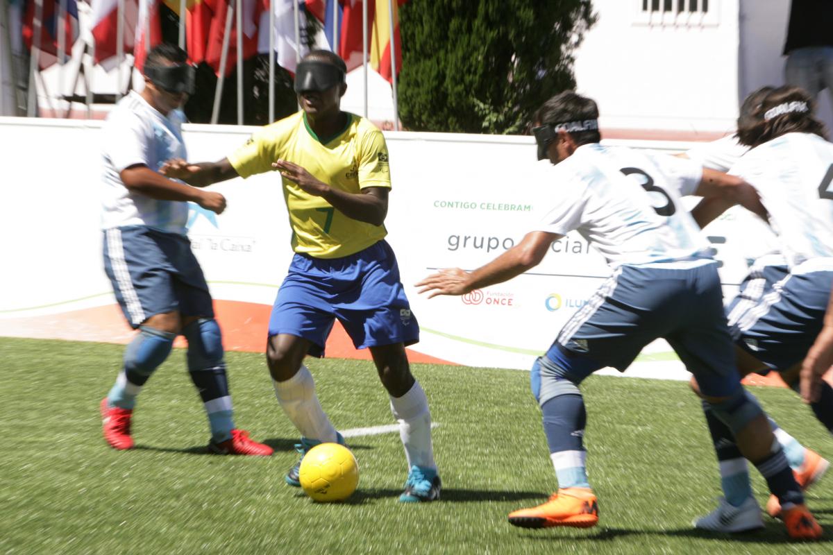 Brazilian vision impaired football dribbles the ball past Argentinian defenders