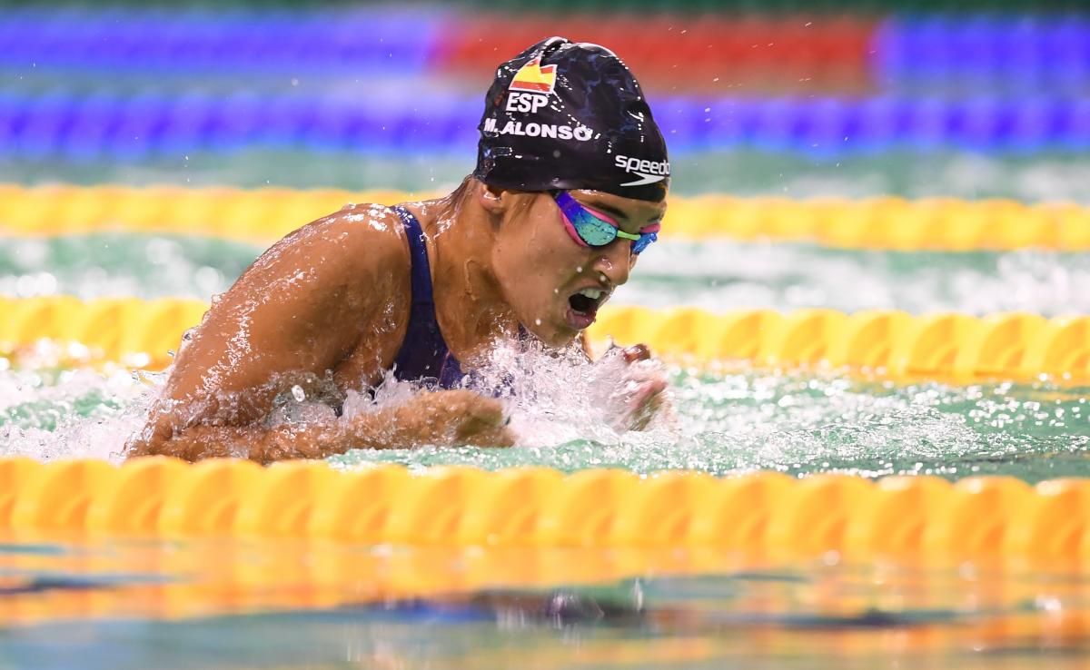 Woman swimming in the pool wearing a black cap with the Spanish flag