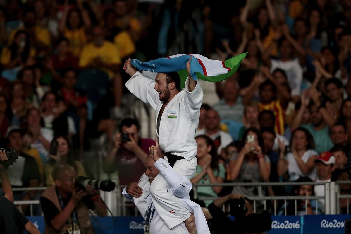 A man carrying Uzbekistan's flag on another man's shoulder