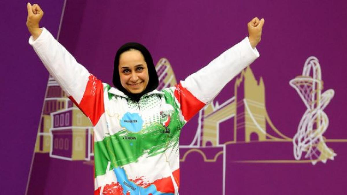 female Para shooter Sareh Javanmardi raises her arms on the podium