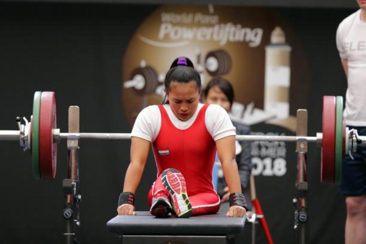 Ni Nengah Widiasih - Indonesia - powerlifting Woman bows head as she sits on powerlifting bench preparing to lift the bar