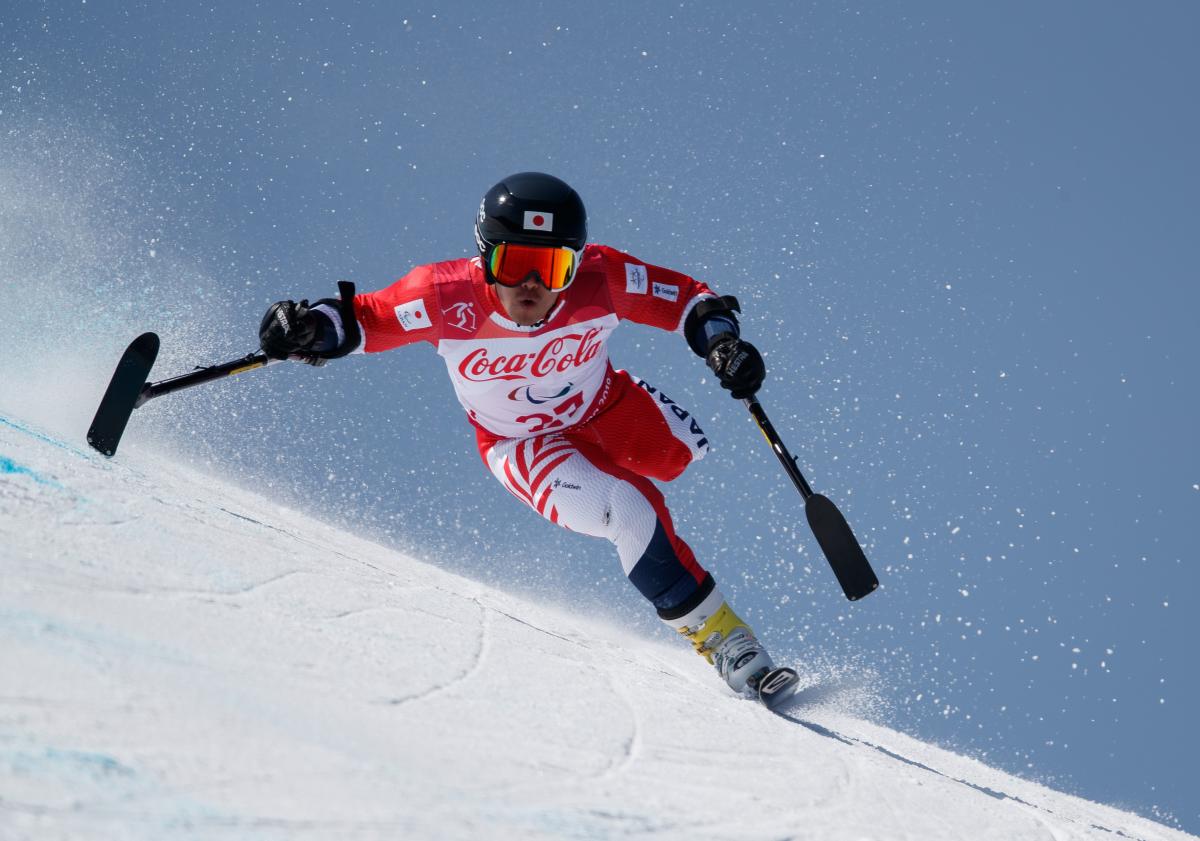 a male Para alpine skier on one leg goes through a gate