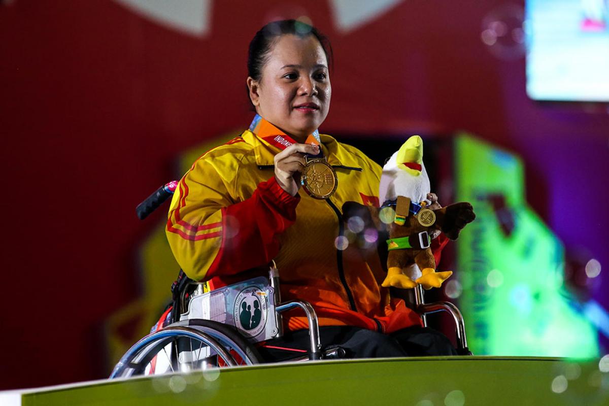 female powerlifter Dang Thi Linh Phuong on the podium holding up her gold medal