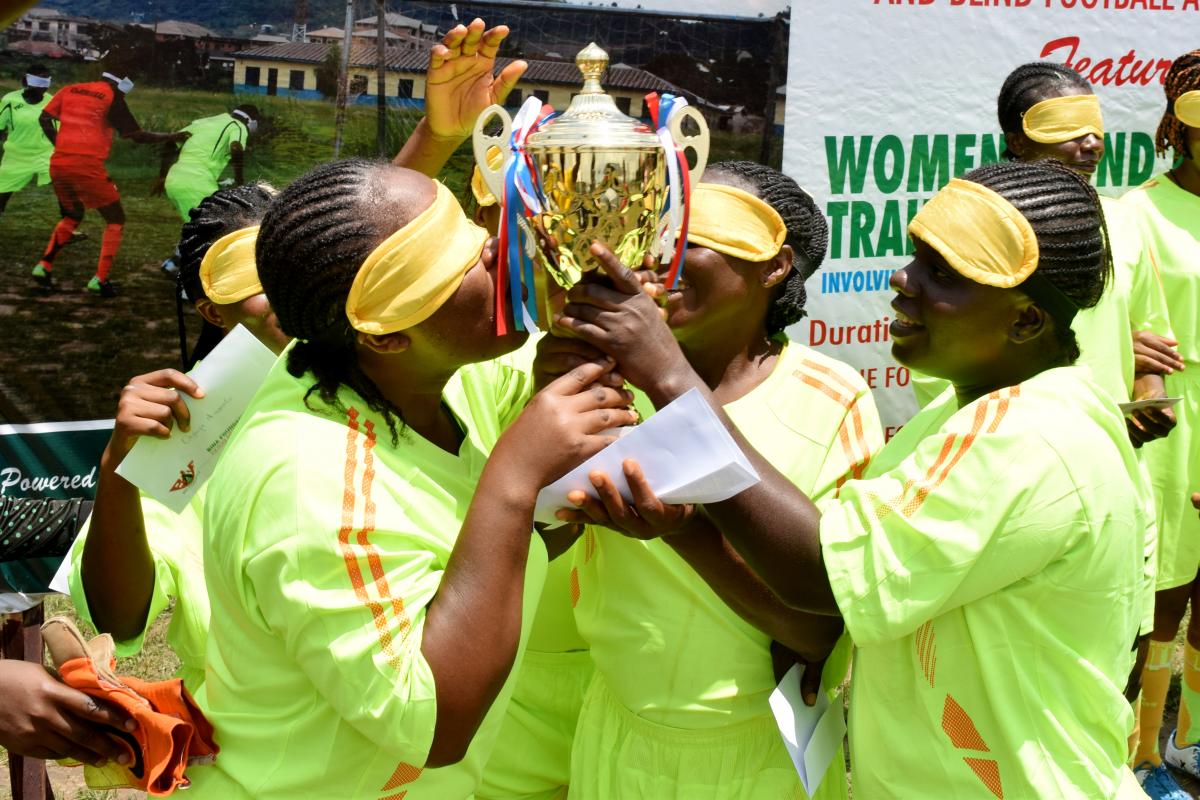four female blind footballers kissing a trophy