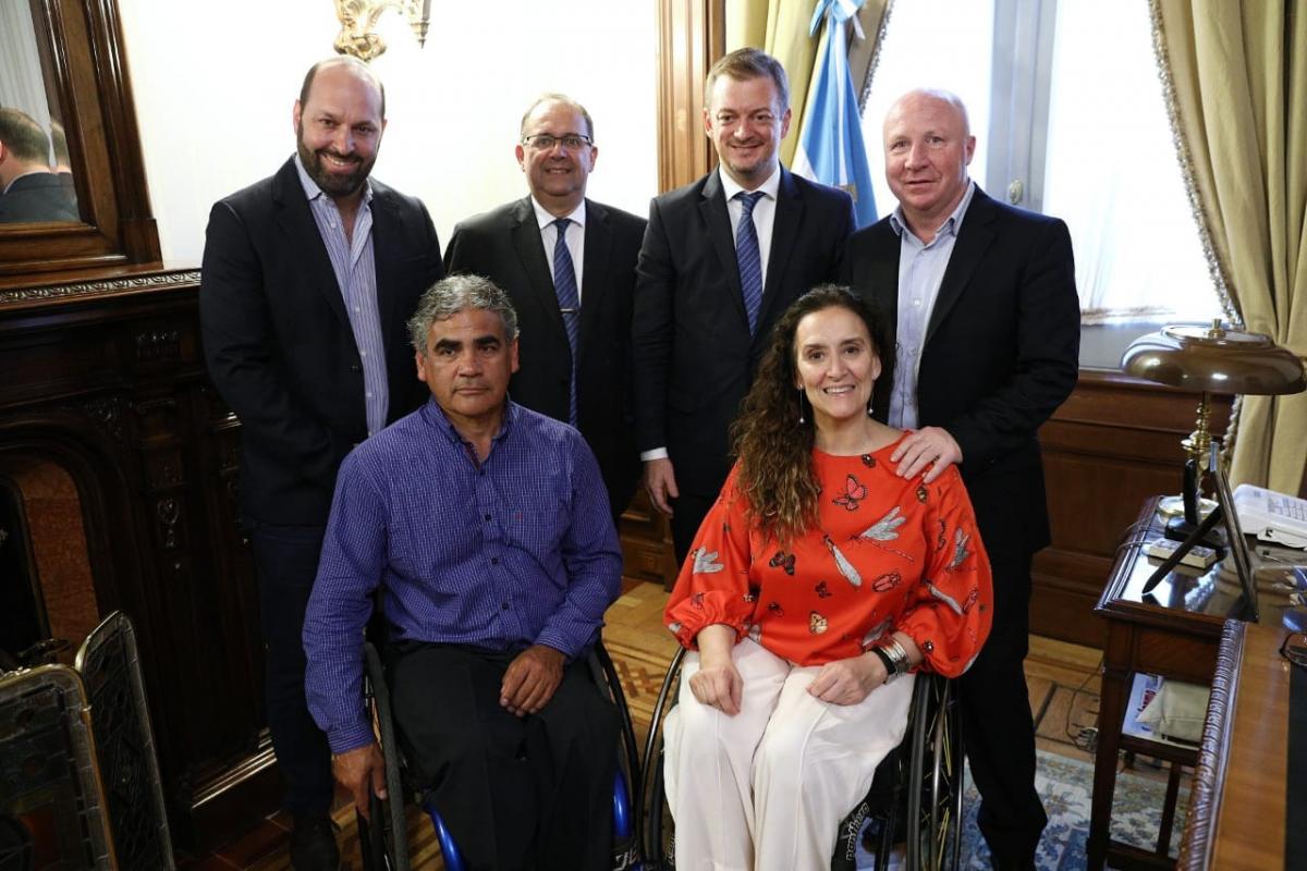 a group of people with Andrew Parsons at the centre in an official flag room