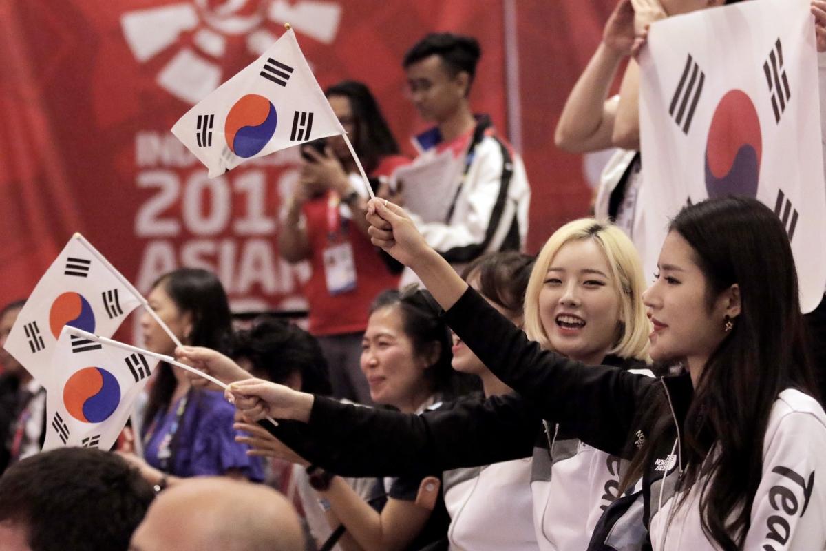 a group of men and women waving South Korean flags