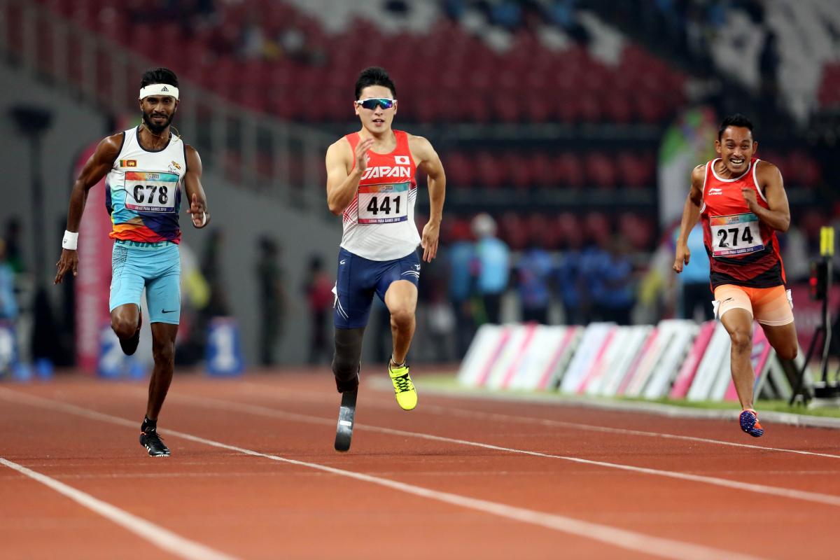 three male sprinters with Shunsuke Itani in the centre run down the 100m track