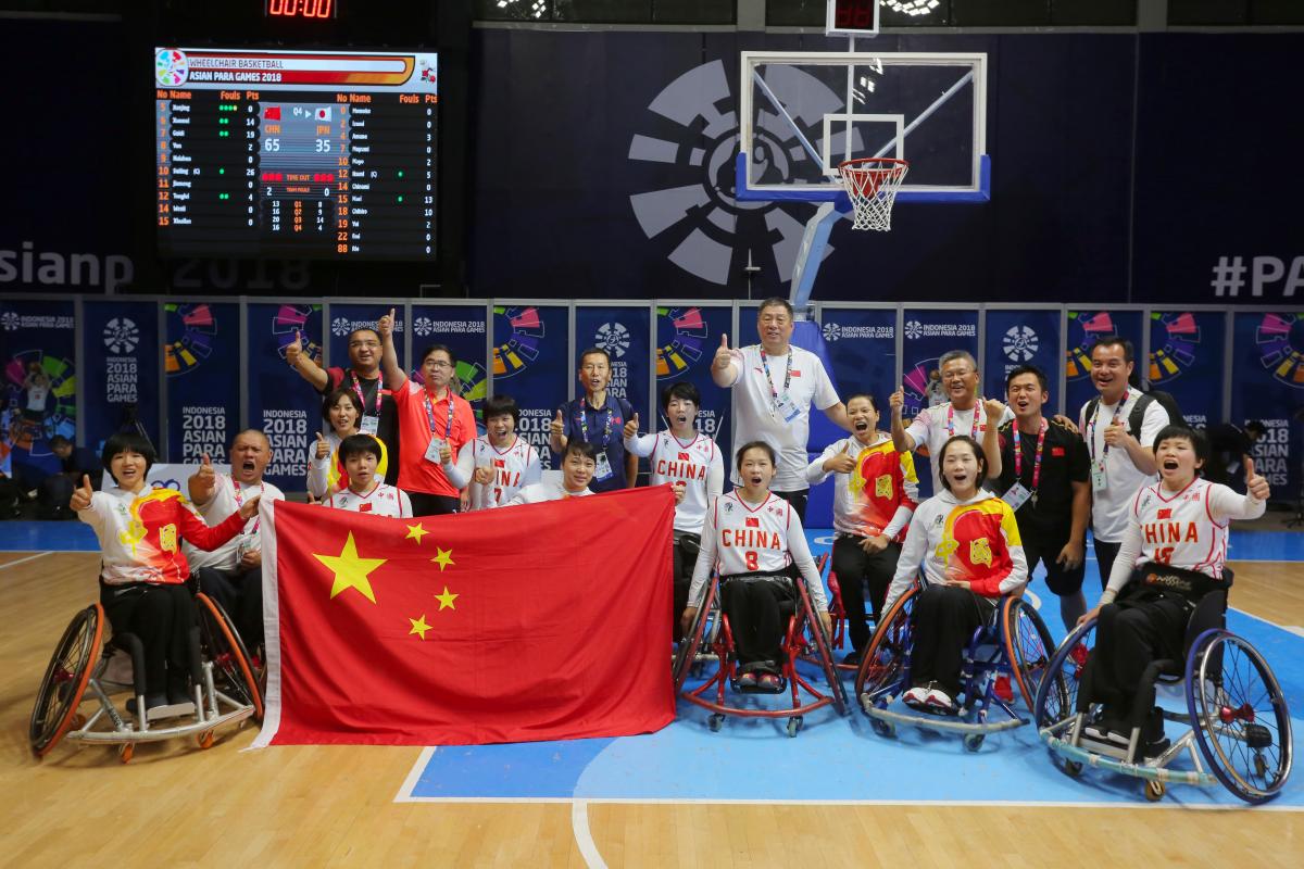 a female Chinese wheelchair basketballer shields the ball from another player