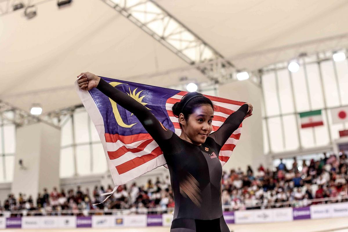 Nur Azlia Syafinaz Mohd Zais - Indonesia 2018 female Para cyclist Nur Azlia Syafinaz Mohd Zais holds up a Malaysia flag