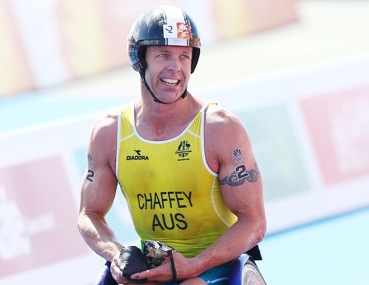 male Para triathlete Bill Chaffey smiles after crossing the finish line in his wheelchair