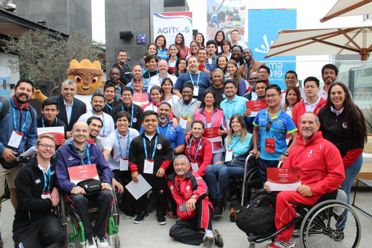 a group of people and the Lima 2019 mascot smile for a photo