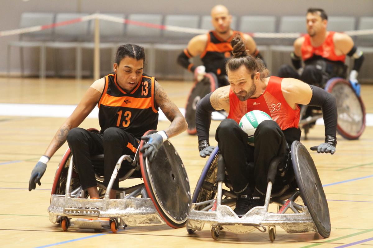 Two male wheelchair rugby players collide with their wheelchairs 